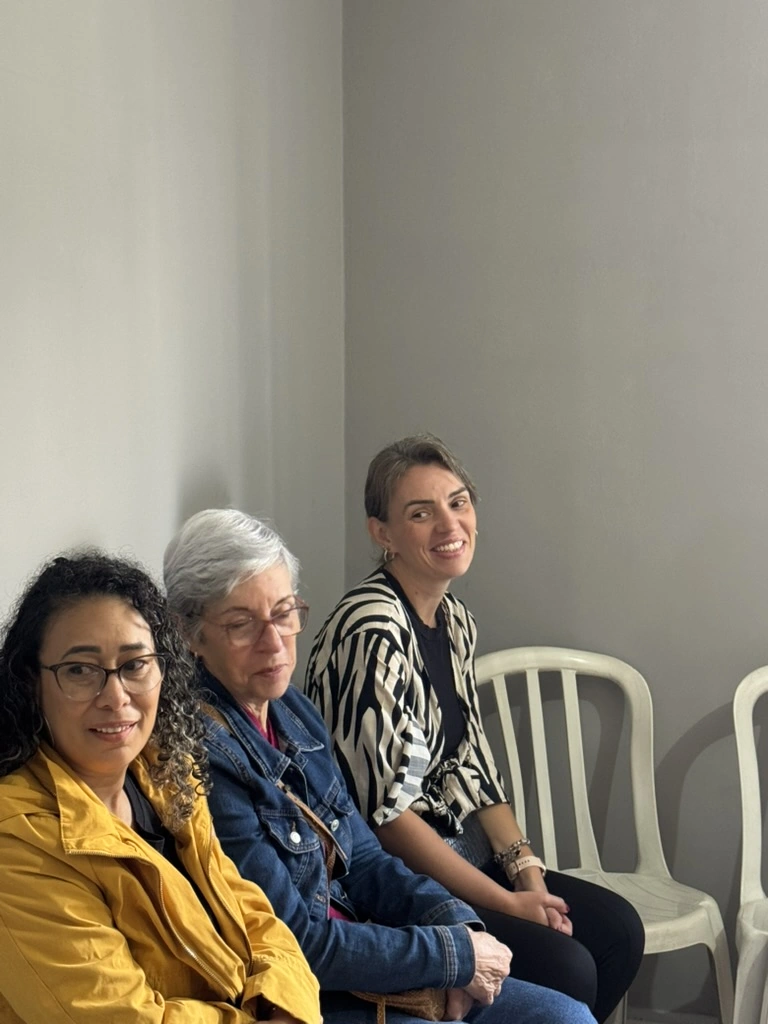 Três participantes conversam sentadas lado a lado durante o encontro.