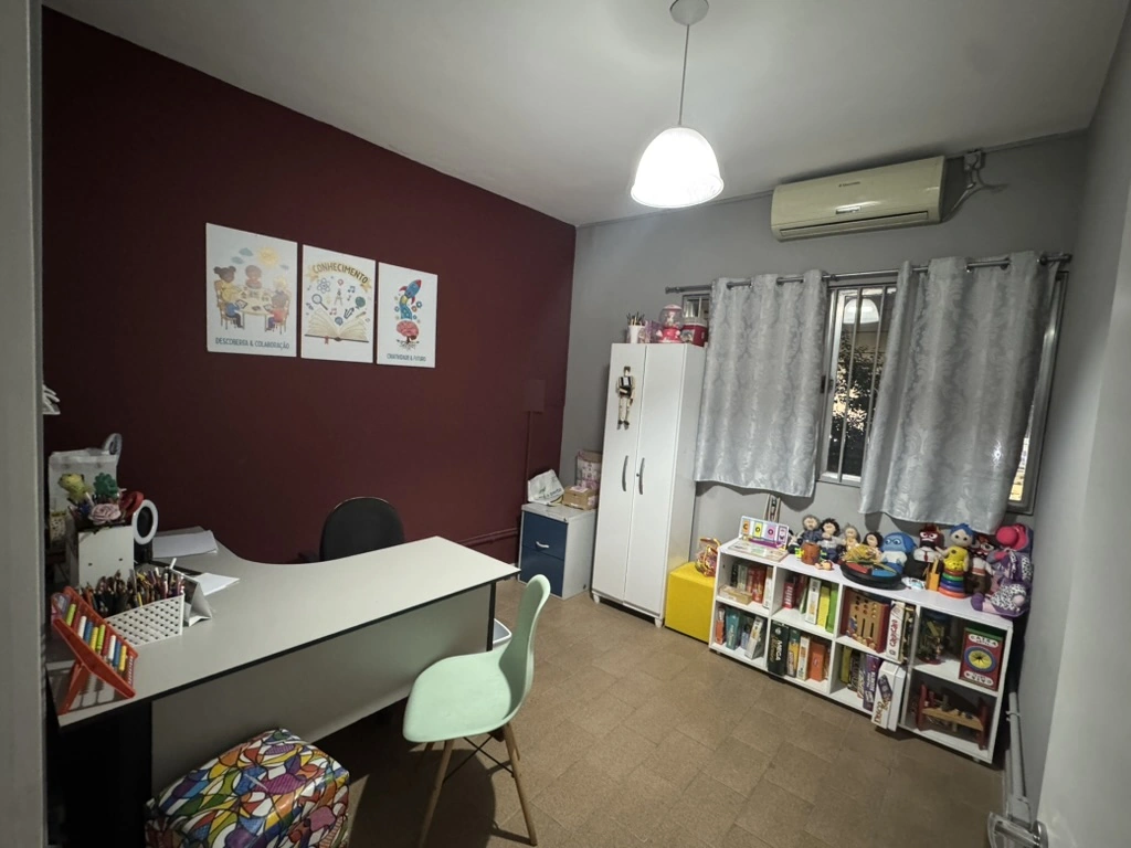 Vista ampla da sala de atendimento com mesa de atividades, estantes de jogos e materiais pedagógicos.